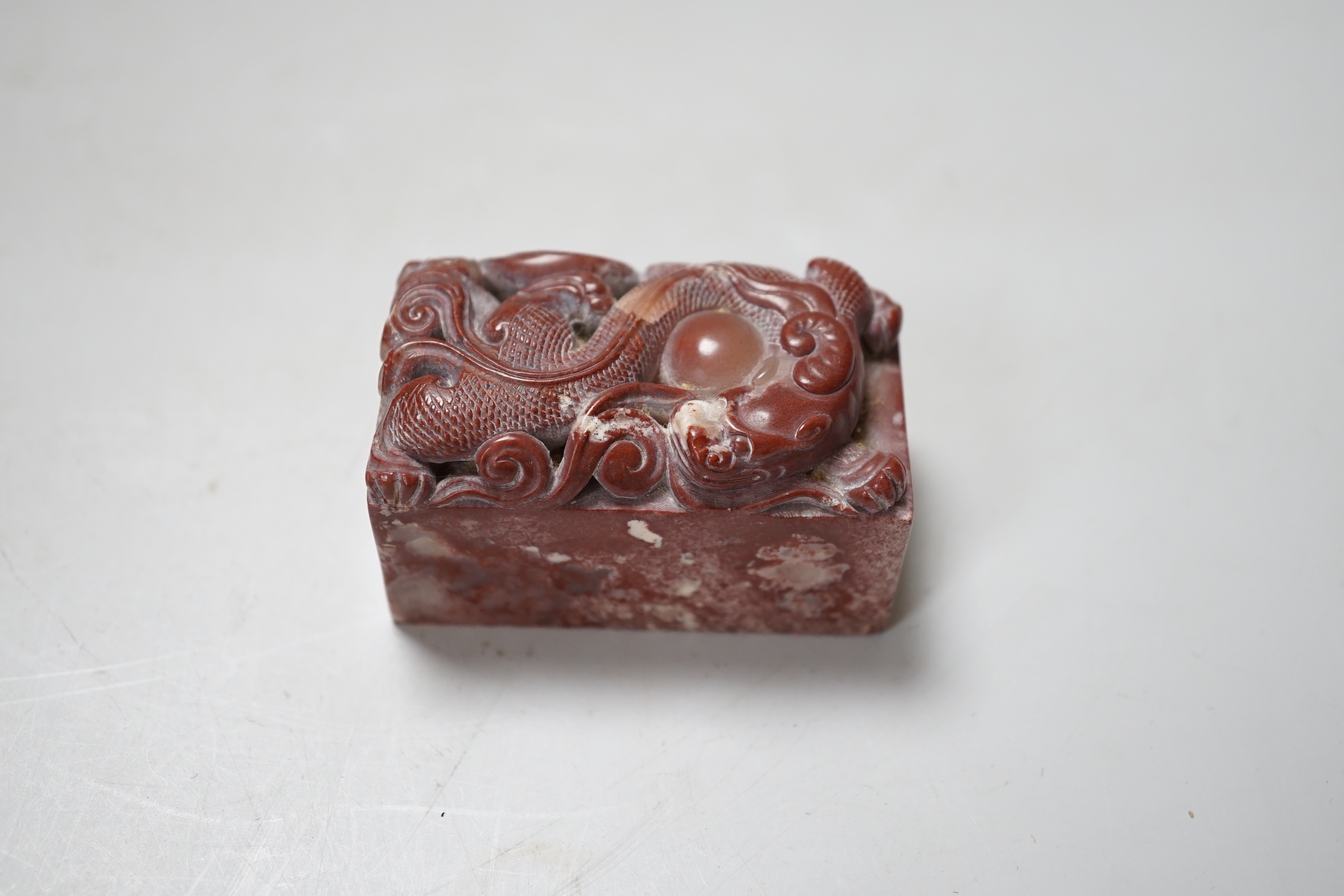 A Chinese chicken’s blood inscribed soapstone seal, carved with a dragon, 6cm